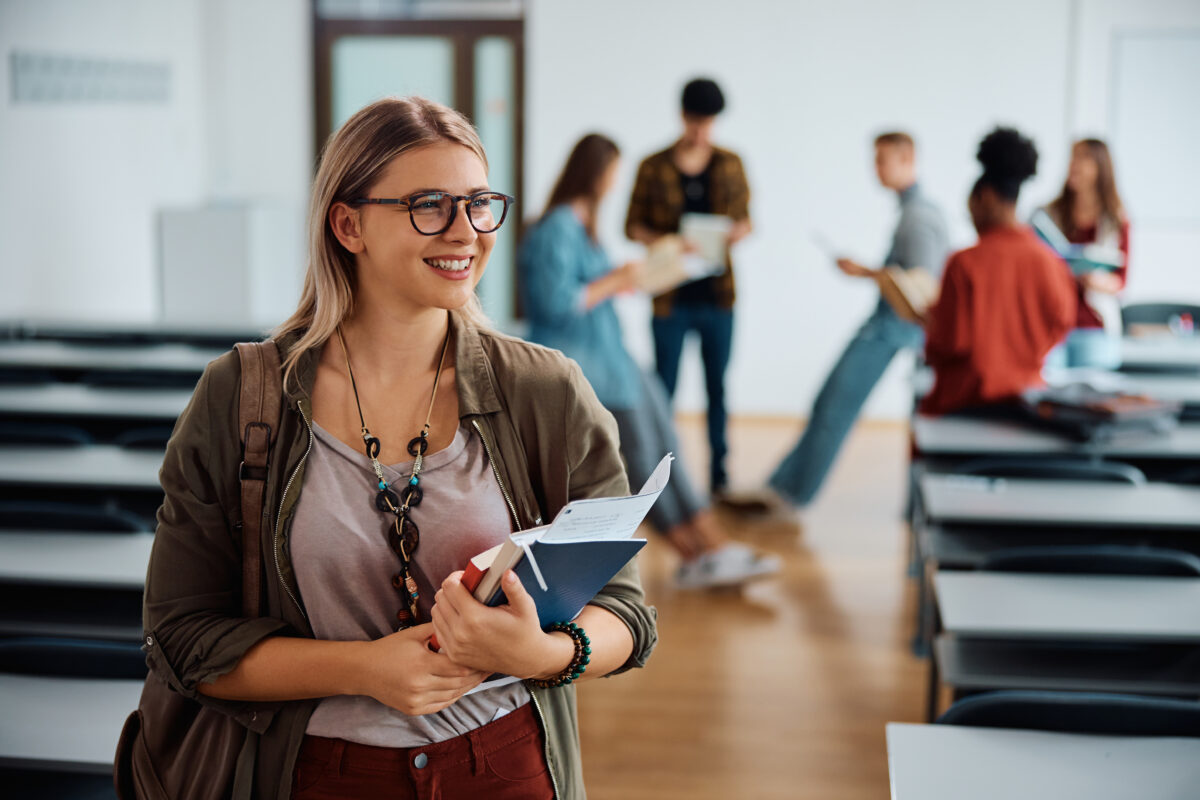 Happy female college student in lecture hall looking away.